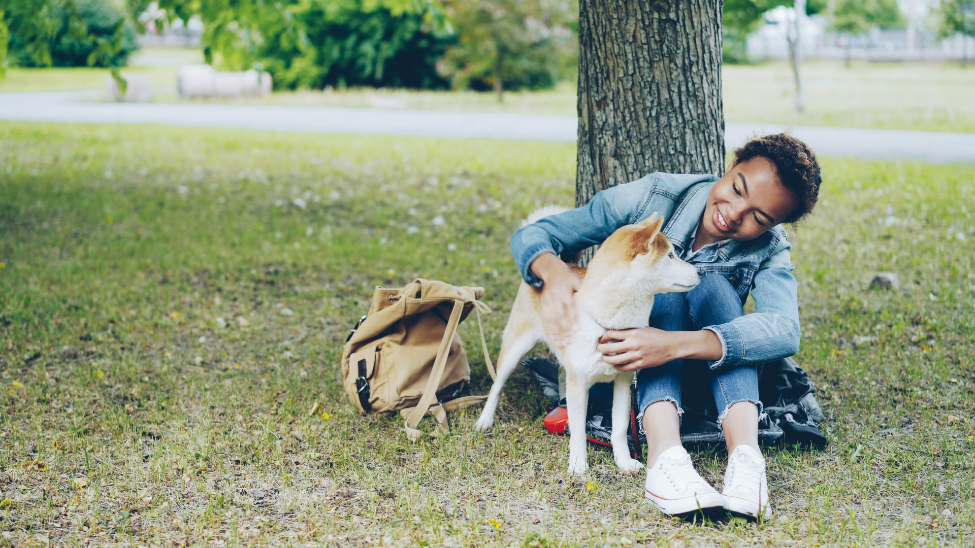 Teen sitting with a dog in a park