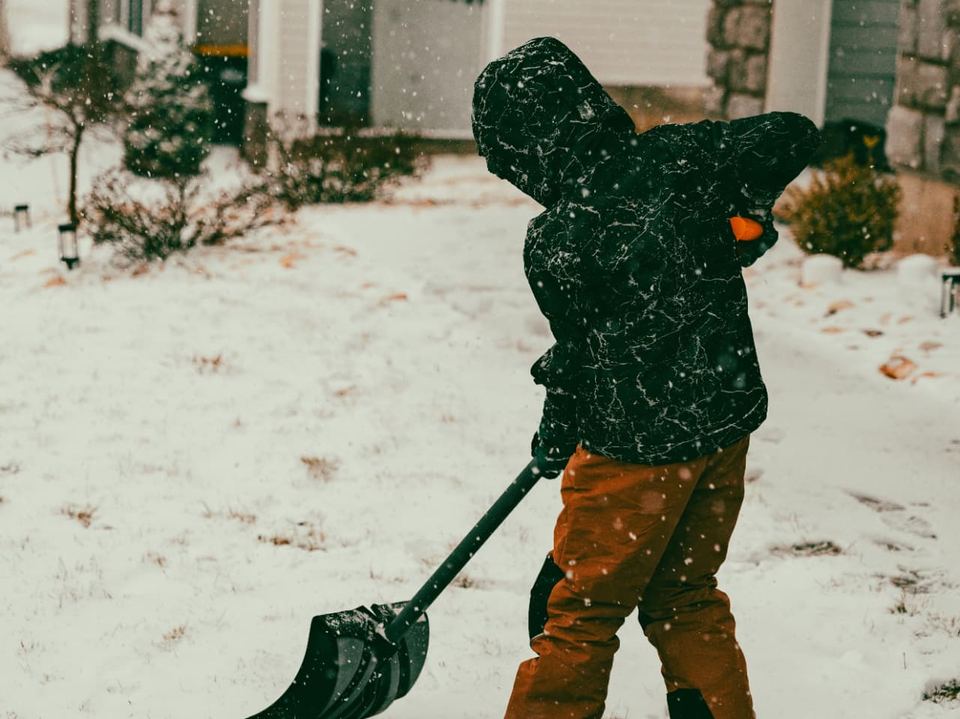 Person shoveling snow in a suburban neighborhood